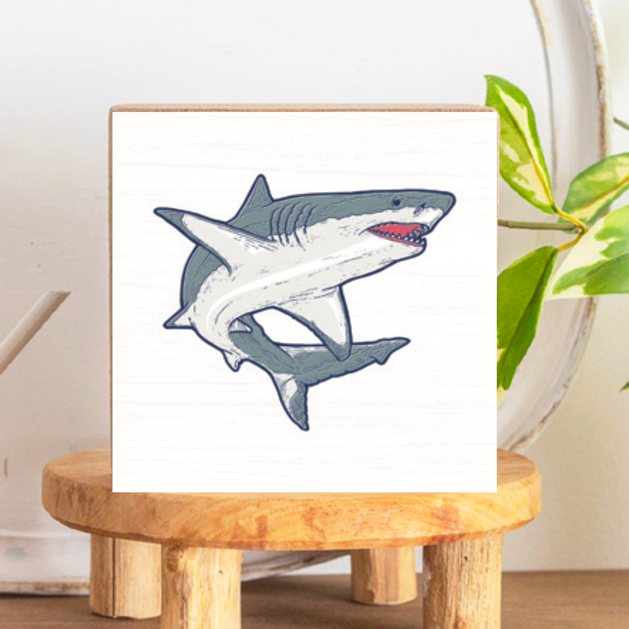 A decorative wooden block featuring a gray shark illustration on a white background, placed on a wooden stand. Available at Be Charmed