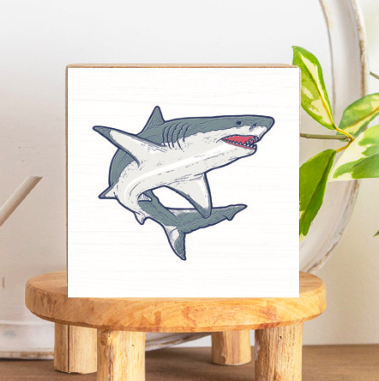 A decorative wooden block featuring a gray shark illustration on a white background, placed on a wooden stand. Available at Be Charmed