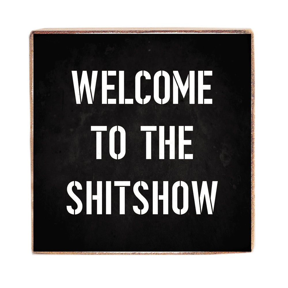 A black 6 x 6 decorative Rustic Marlin wood block with white text that reads 'WELCOME TO THE SHITSHOW'. Available at Be Charmed.