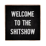 A black 6 x 6 decorative Rustic Marlin wood block with white text that reads 'WELCOME TO THE SHITSHOW'. Available at Be Charmed.