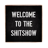 A black 6 x 6 decorative Rustic Marlin wood block with white text that reads 'WELCOME TO THE SHITSHOW'. Available at Be Charmed.