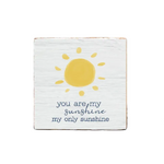 A decorative wooden block with a sun illustration and the text 'you are my sunshine my only sunshine' on it, placed on a wooden surface. Available at Be Charmed