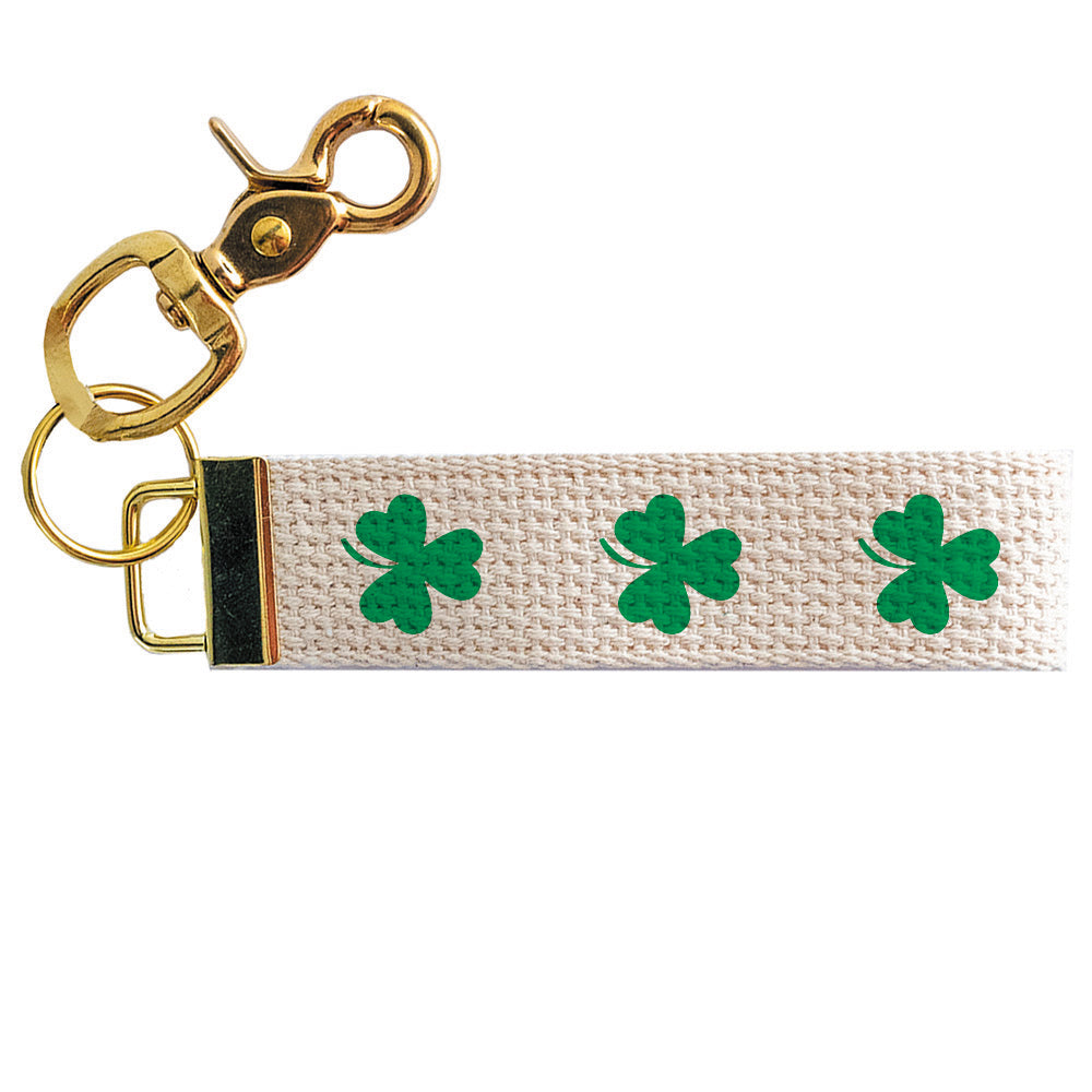 Keychain with green shamrock designs on a beige strap with gold clasp. Available at Be Charmed
