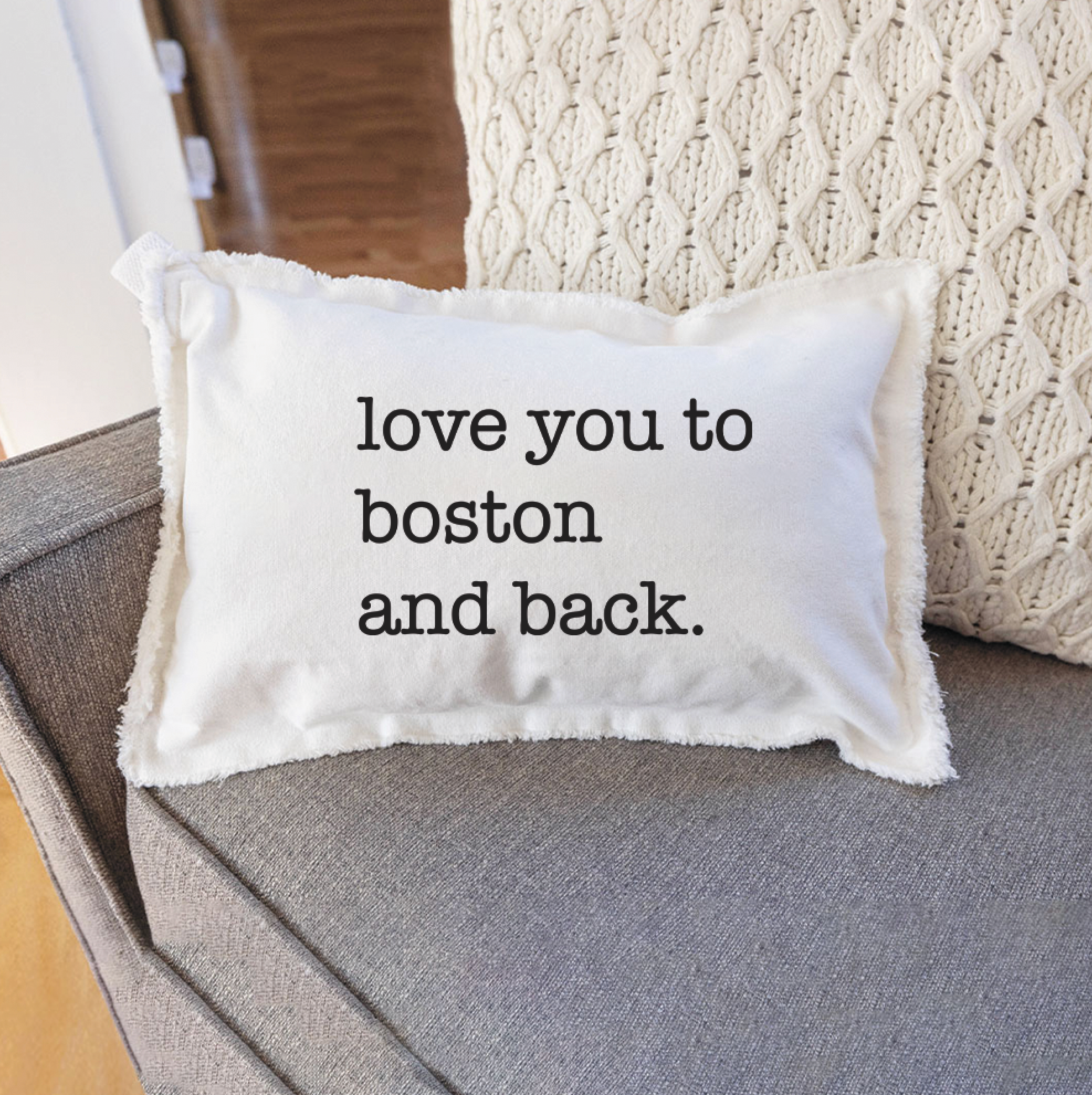 Rustic Marlin "Love You to Boston" 12x18 Pillow pictured on chair - Handcrafted in New England, this pillow adds Boston charm to any space. Available at Be Charmed Gifts.