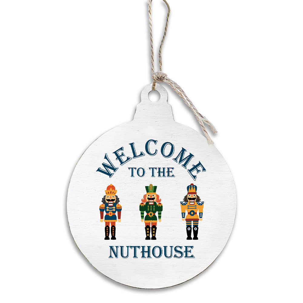 Round white ornament with nutcrackers and 'Welcome to the Nuthouse' text on a white background. Available at Be Charmed