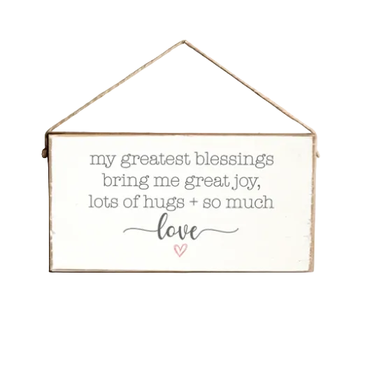 A rustic style twine hanging sign made of pine wood with the text 'My Greatest Blessings Bring Me Great Joy, Lots of Hugs + So Much Love' and a heart symbol. Available at Be Charmed