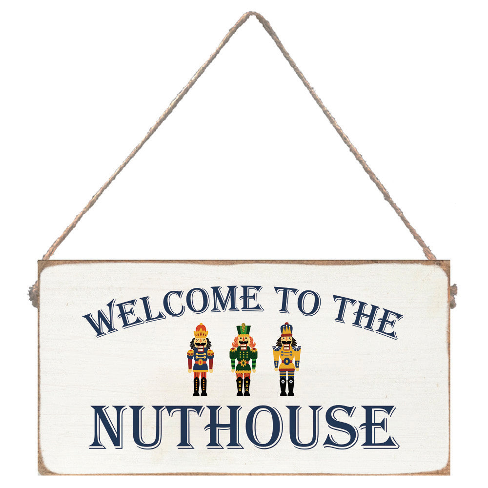 Decorative sign with 'Welcome to the Nuthouse' text and three nutcrackers on a white background. Available at Be Charmed