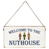Decorative sign with 'Welcome to the Nuthouse' text and three nutcrackers on a white background. Available at Be Charmed