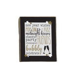 A decorative wooden block with a list of New Year's wishes written in a poetic format, accompanied by the word 'BUBBLY' at the bottom, indicating a celebratory tone. The block is dark in color with gold stars and a silver line drawing of a champagne bottle. Available at Be Charmed