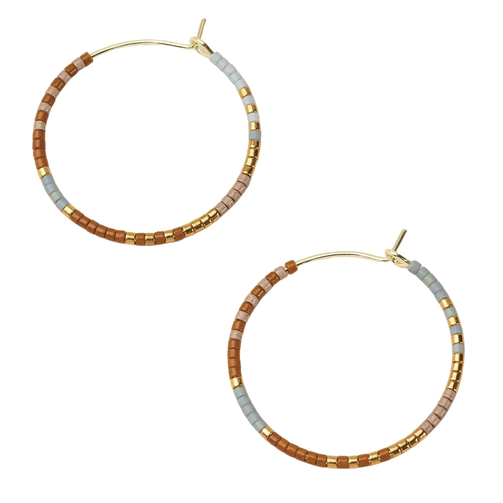Pair of beaded hoop earrings with gold accents on a beige background. Available at Be Charmed