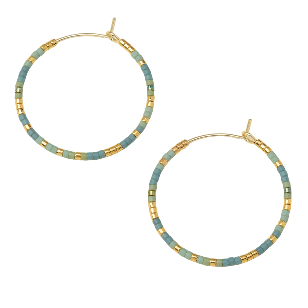 Hoop earrings with blue and gold beads on a beige background. Available at Be Charmed
