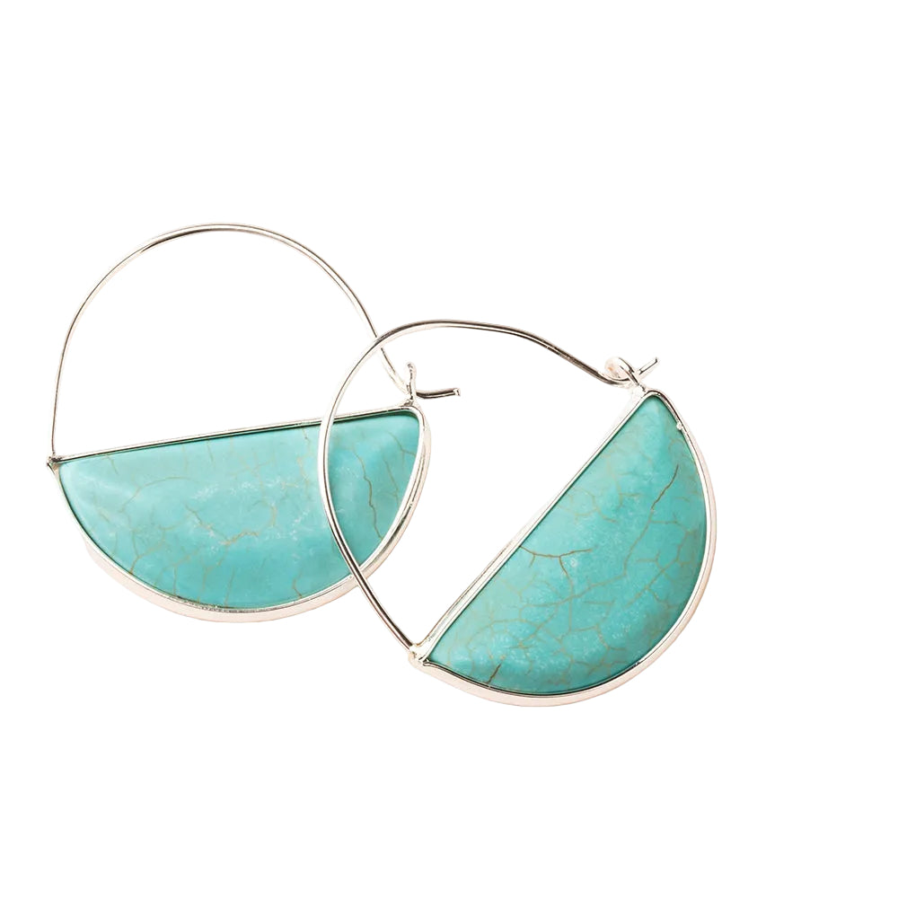 Turquoise and silver hoop earrings on a light pink background