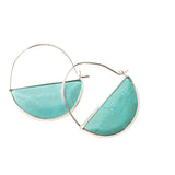 Turquoise and silver hoop earrings on a light pink background