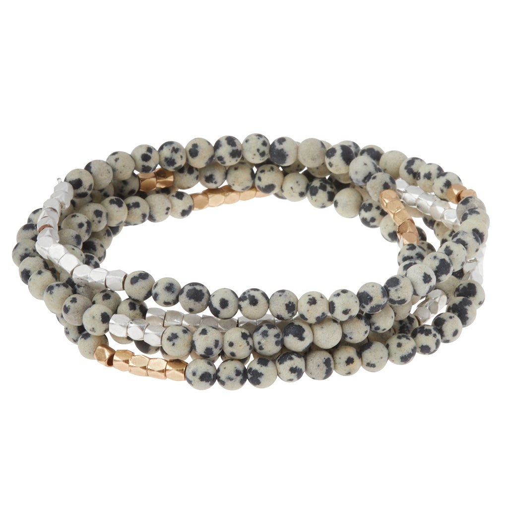 Stack of beaded bracelets with white, black, and gold beads on a white background. Available at Be Charmed