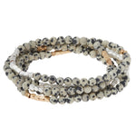 Stack of beaded bracelets with white, black, and gold beads on a white background. Available at Be Charmed