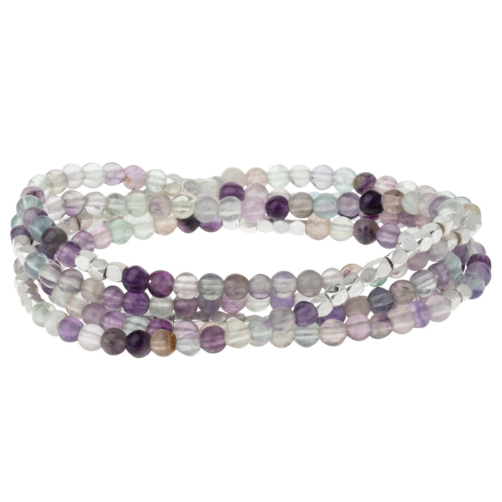 Multistrand beaded bracelet with purple and white beads on a white background. Available at Be Charmed