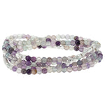 Multistrand beaded bracelet with purple and white beads on a white background. Available at Be Charmed