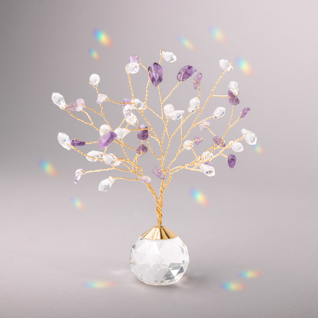 Decorative crystal suncatcher with purple and clear stones in a clear vase on a gray background. Available at Be Charmed