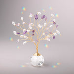 Decorative crystal suncatcher with purple and clear stones in a clear vase on a gray background. Available at Be Charmed