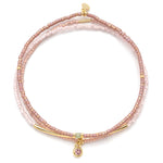 Pink beaded bracelet with gold accents and a pink gemstone charm on a white background. Available at Be Charmed