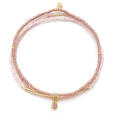 Pink beaded bracelet with gold accents and a pink gemstone charm on a white background. Available at Be Charmed