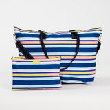 Fall in Line SCOUT Overpacker Large Foldable Travel Bag – 22″W × 14.5″H × 7″D lightweight poly‑canvas tote with interior zipper pouch that converts to a pocket. Holds up to 50 lbs, includes trolley sleeve and removable shoulder strap. Available at Be Charmed