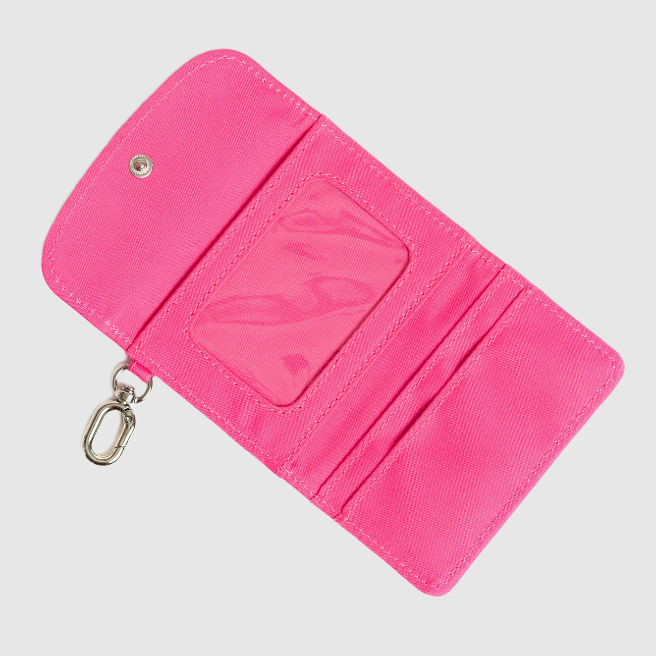 Pink wallet with a keychain on a light gray background. Available at Be Charmed
