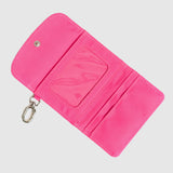 Pink wallet with a keychain on a light gray background. Available at Be Charmed