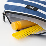 Yellow comb and bottle in a blue and white striped pouch with a brand logo. Available at Be Charmed