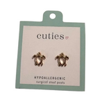 A pair of turtle-shaped stud earrings on a mint green and white card labeled 'cuties hypoallergenic surgical steel posts'. Available at Be Charmed