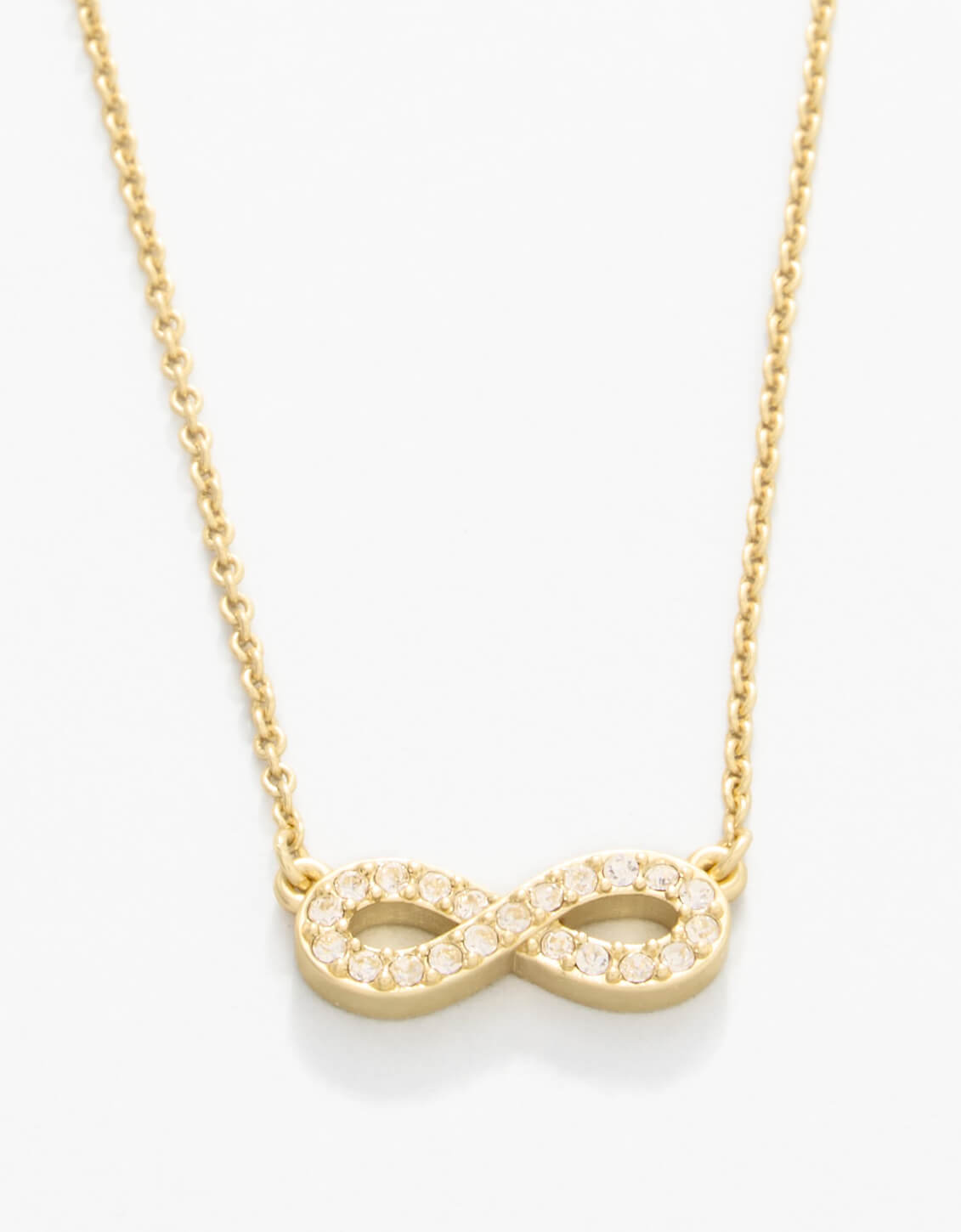 Gold infinity necklace on a white background. Available at Be Charmed