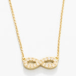 Gold infinity necklace on a white background. Available at Be Charmed