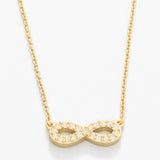Gold infinity necklace on a white background. Available at Be Charmed