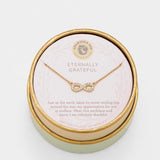 Gold necklace in a round jewelry box with a message on a white background. Available at Be Charmed