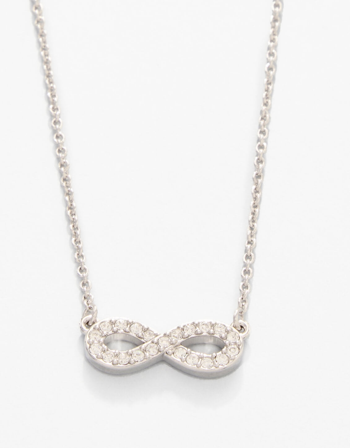 Silver infinity necklace with clear stones on a white background. Available at Be Charmed