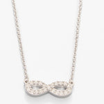 Silver infinity necklace with clear stones on a white background. Available at Be Charmed