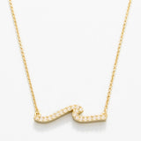 Gold necklace with a wavy design on a white background. Available at Be Charmed