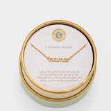 Gold 'mama' necklace in a round box with a message card on a light gray background. Available at Be Chamred