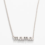 Silver necklace with 'mom' pendant on a white background. Available at Be Charmed