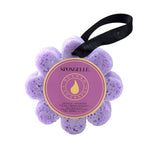 A purple bath sponge with a flower-like shape, labeled Spongellé with the word 'Wild Flower' and 'French Lavender'. There is a black string attached for hanging. Available at Be Charmed