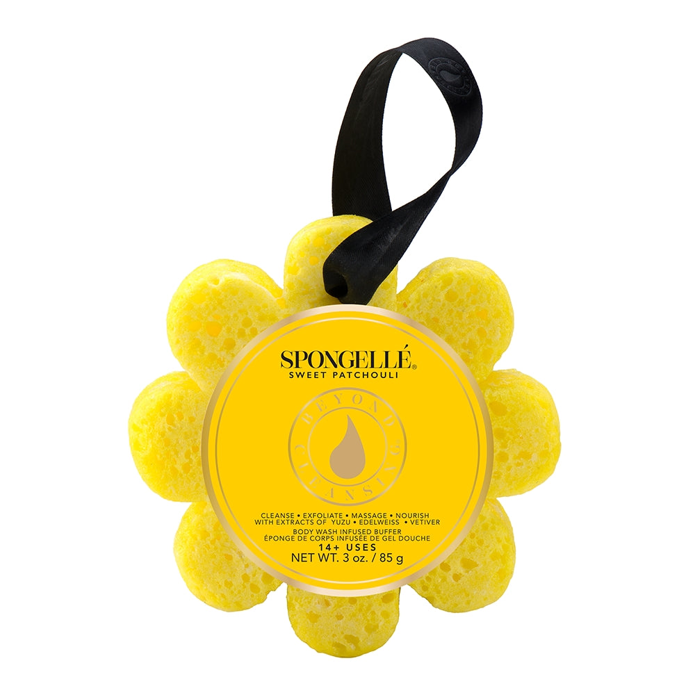 A yellow Spongellé bath sponge in the shape of a flower with a black hanging ribbon, packaging displays product information. Available at Be Charmed