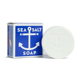 A bar of soap with a blue and white label that reads 'Sea Salt Soap', next to its blue box packaging with a similar design and text. Available at Be Charmed