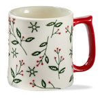 White mug with red handle featuring green leaf and snowflake pattern on a white background.  Available at Be Charmed