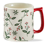 White mug with red handle featuring green leaf and snowflake pattern on a white background.  Available at Be Charmed