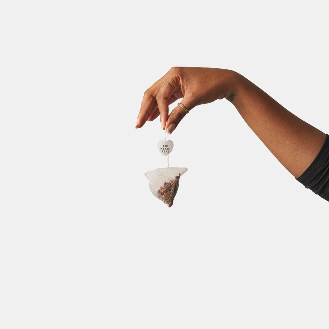 Person holding tea bag of Big Heart Tea Co Tea For Two Cup of Love calming rose herbal tea for two – Available at Be Charmed