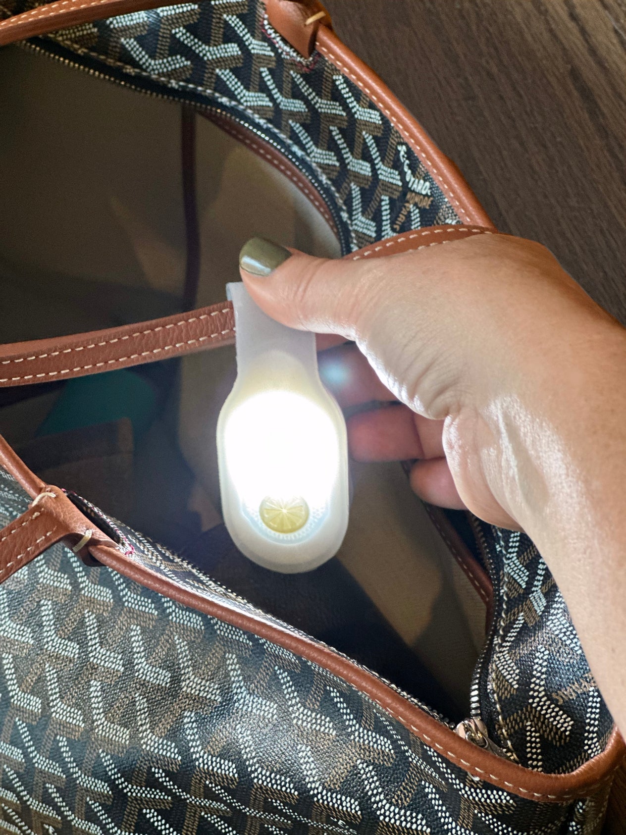 Hand holding a small Tech Candy Magnetic Clip Light near a patterned bag. Available at Be Charmed
