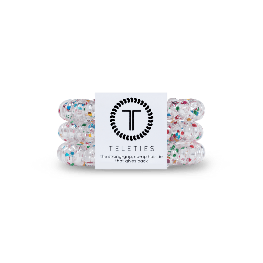 Pack of three Teleties hair ties with a label that reads 'the strong grip, no rip hair tie that doubles as a bracelet. Strong, pretty and stylish. Available at Be Charmed