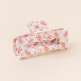 A floral patterned hair claw clip on a light background. Available at Be Charmed