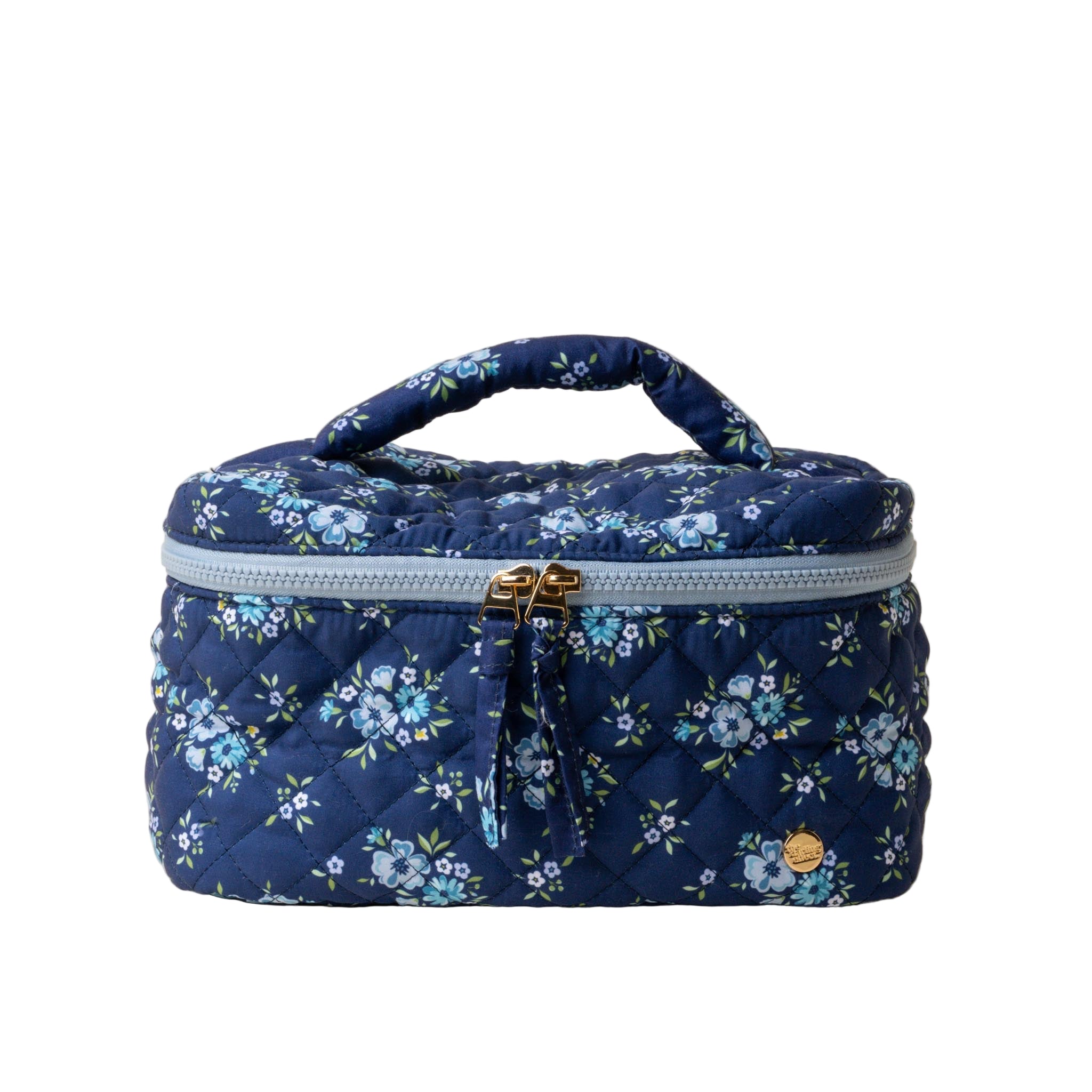 A quilted cosmetic bag with a floral pattern, a pink handle, and a double gold zipper. Available at Be Charmed