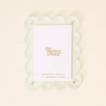 A pale blue mini acrylic picture frame with a scalloped border and the brand 'the darling effect' printed at the bottom. Available at Be Charmed